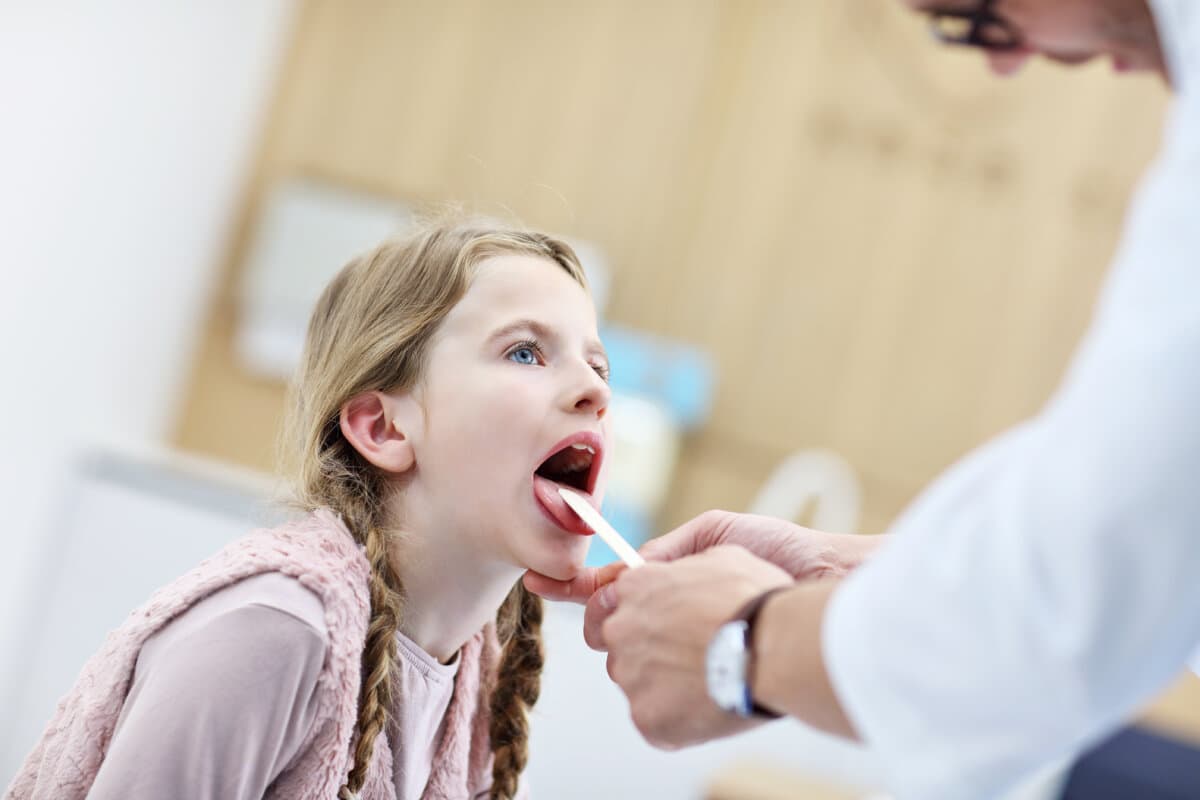 Picture showing little girl in clinic being examined by laryngologist