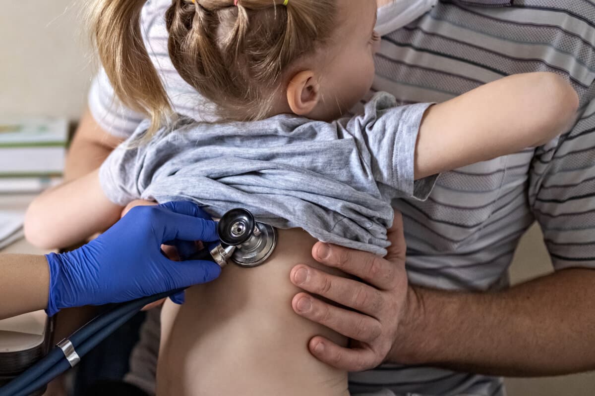 Little girl in the arms of her father in the doctor’s office at the clinic.