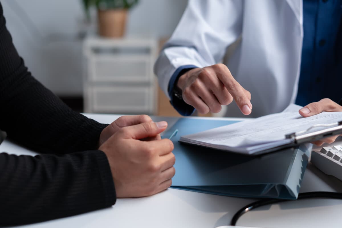 Doctor reviewing medical records with a patient during consultation, explaining healthcare documents, diagnosis, treatment
