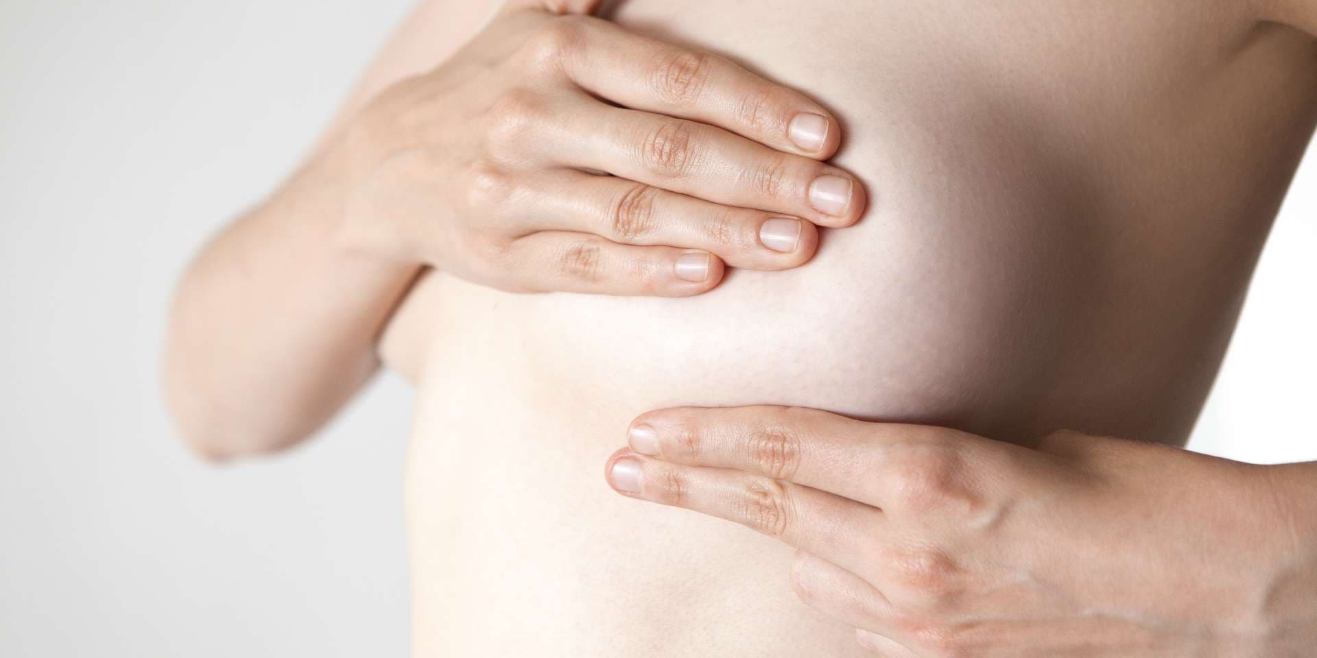 Woman examining her breast with hands