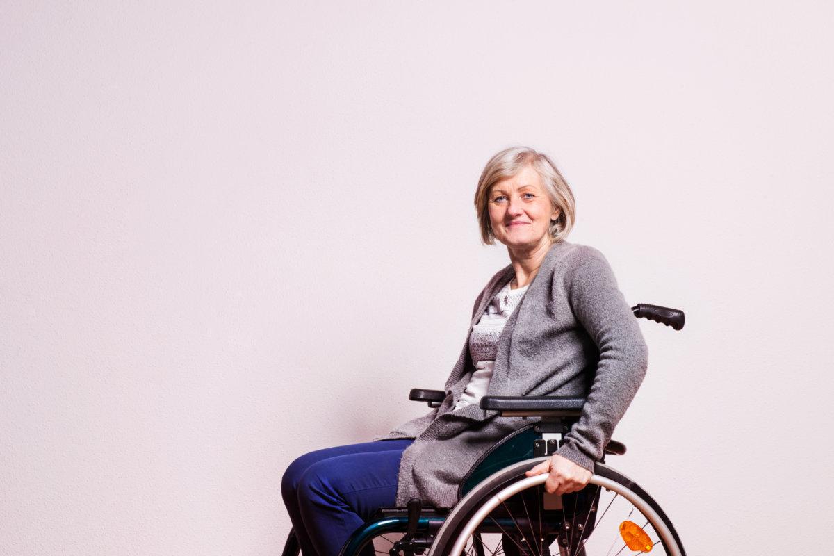 Portrait of a happy senior woman with wheelchair in studio. Copy space.