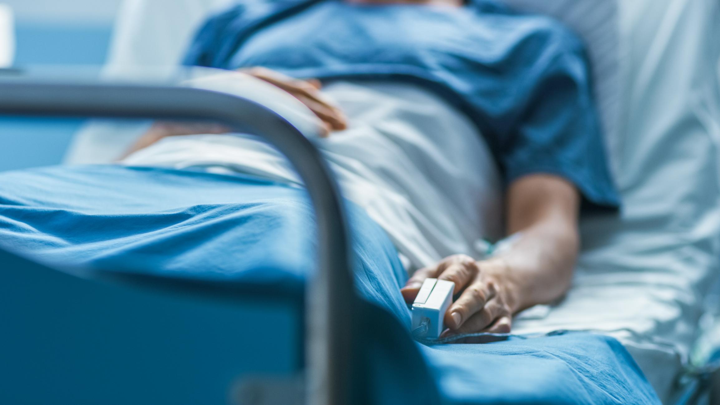 Im Krankenhaus schläft ein kranker männlicher Patient auf dem Bett. Das Gerät zur Herzfrequenzmessung befindet sich an seinem Finger.