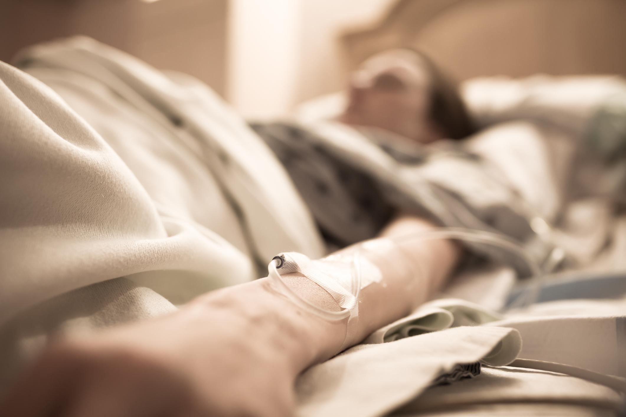 Frau im Krankenhausbett mit iv auf ihrem Arm.