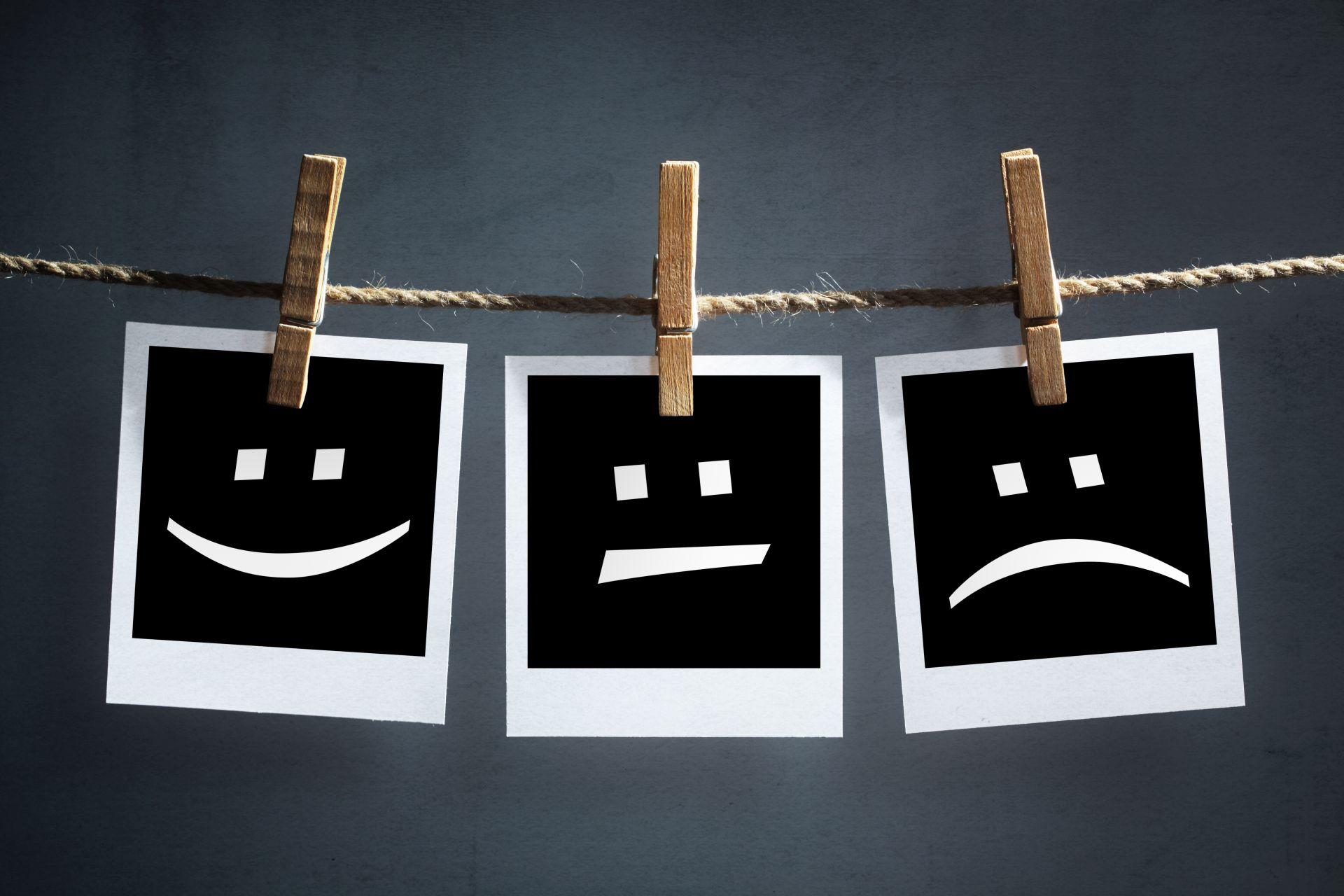Happy, sad and neutral emoticons on instant print transfer photographs hanging on a clothesline