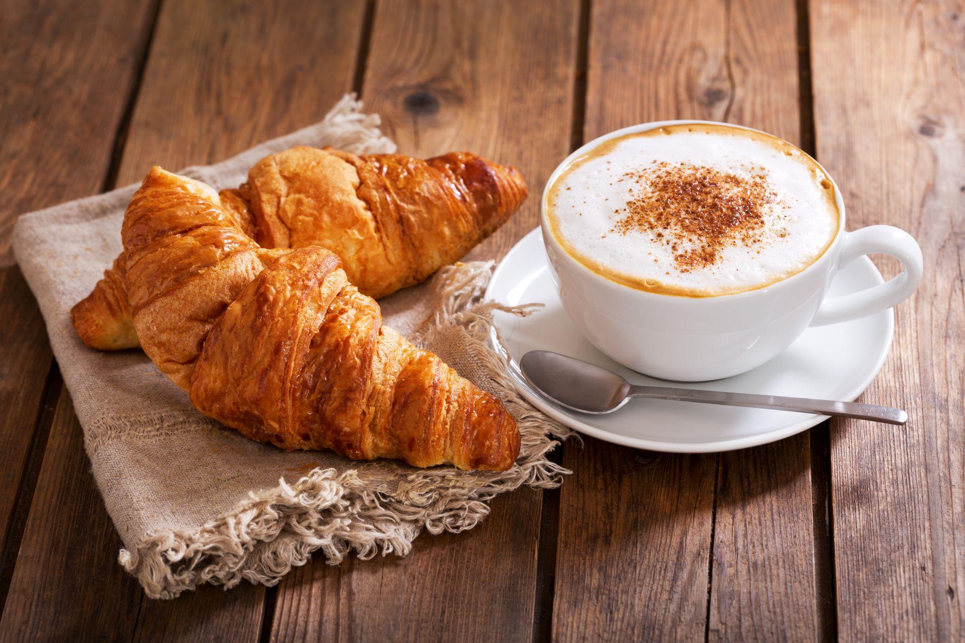Tasse Cappuccino-Kaffee mit Croissants auf Holztisch