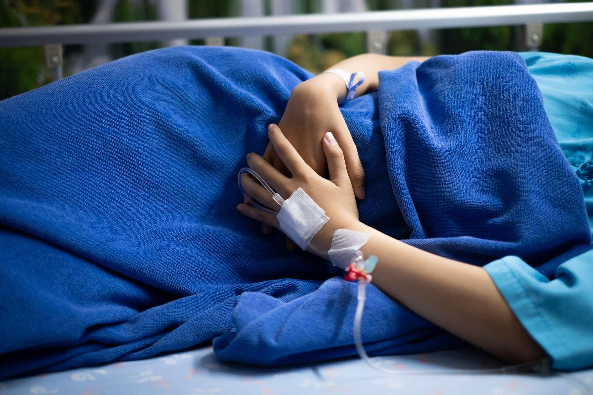 Patientin, die unter Bauchschmerzen leidet, während sie auf Krankenhausbett liegt.