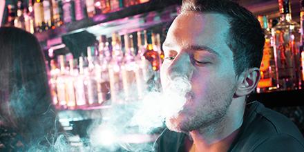 Portrait of young man letting smoke out of mouth while smoking hookah