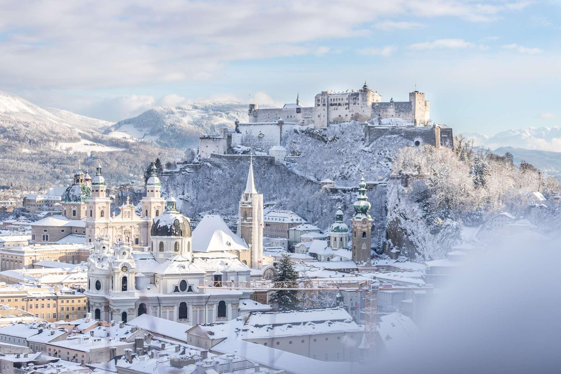 Schneebedeckte Altstadt und Festung Salzburg im Winter, sonniger Tag
