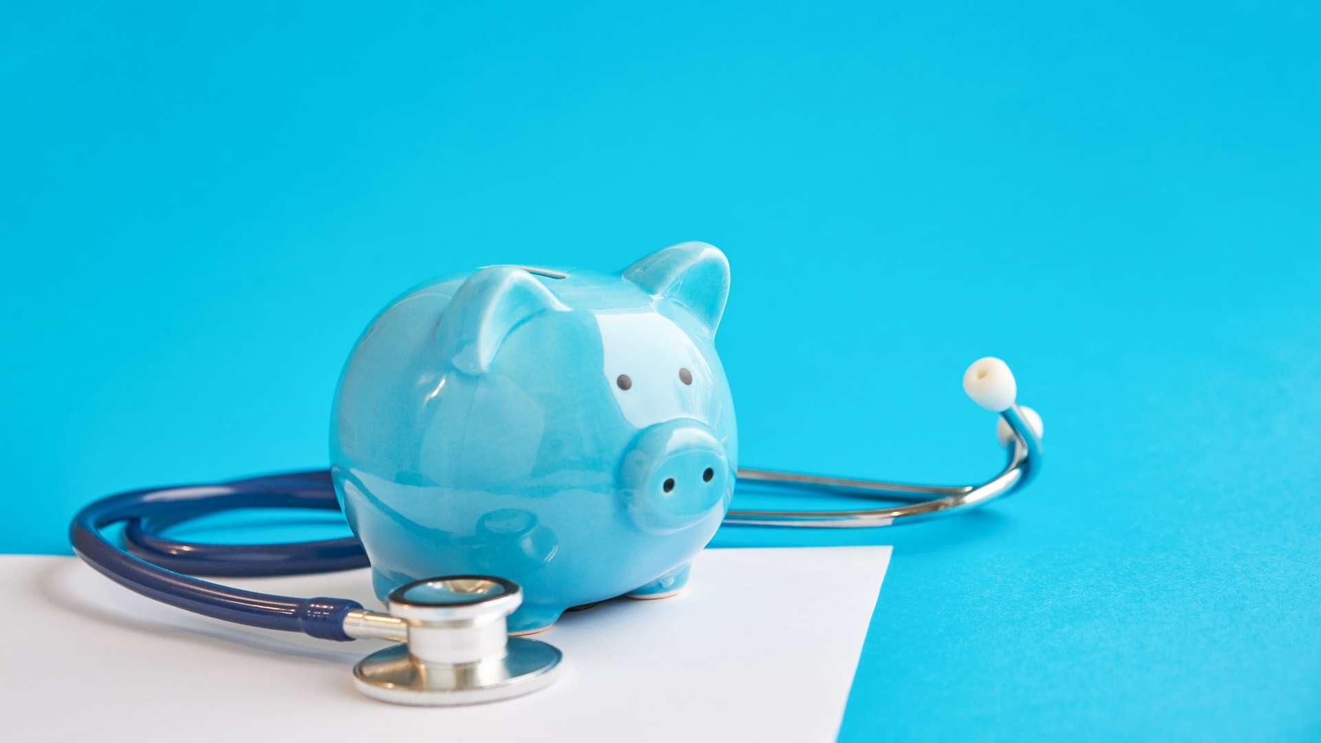 Sparschwein mit Stethoskop auf blauem Hintergrund isoliert. Steuerverrechnungskonzept. Abzüge für medizinische Kosten und Steuererleichterungen