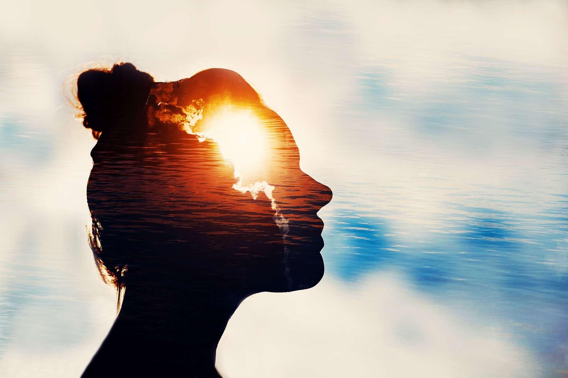 Der Lichtkopf. Schattenbild der jungen Frau auf Himmelhintergrund mit Sonne in ihrem Kopf.