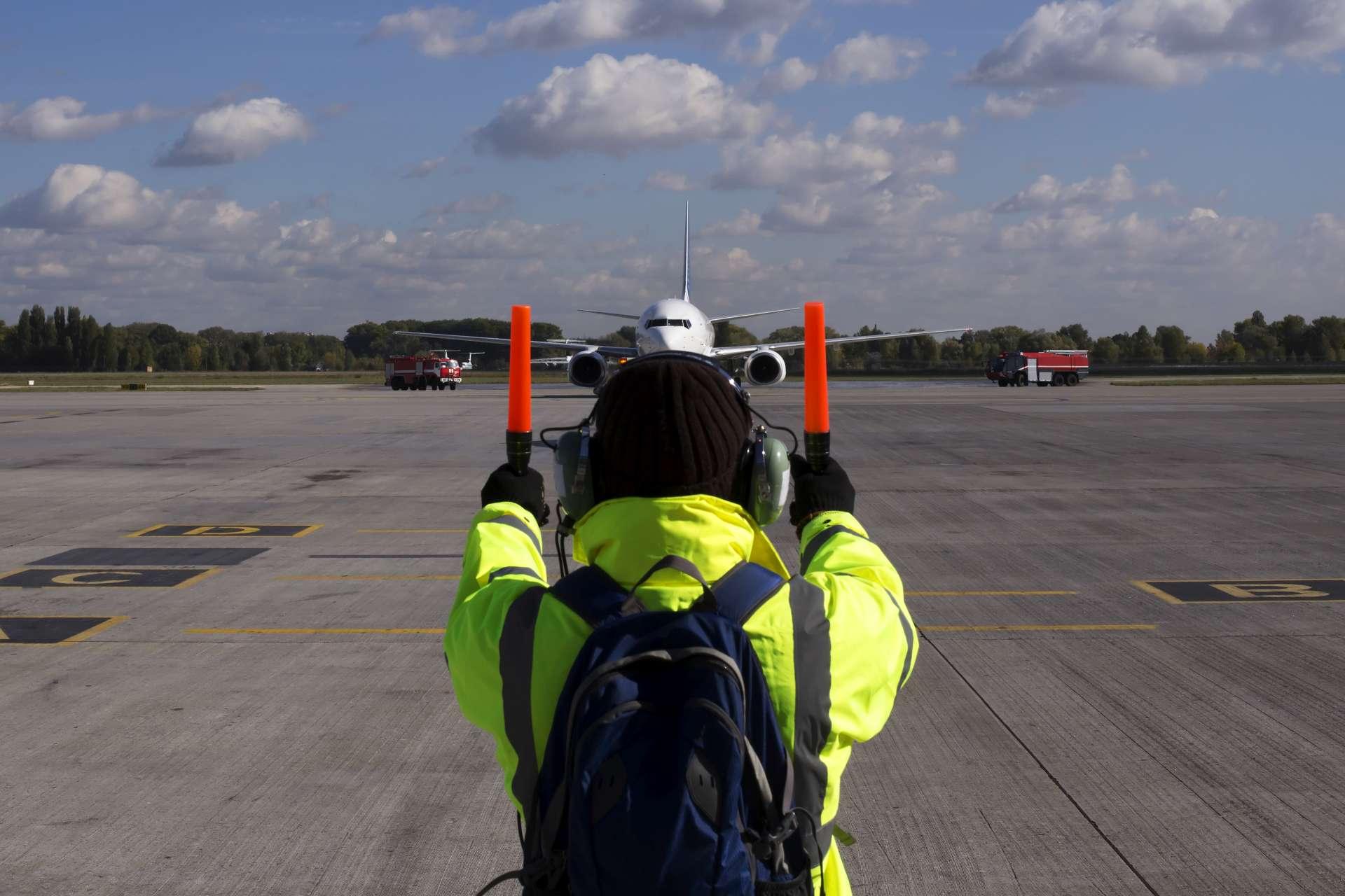 Ein Vorgesetzter hilft beim Flugzeugparken am Flughafen