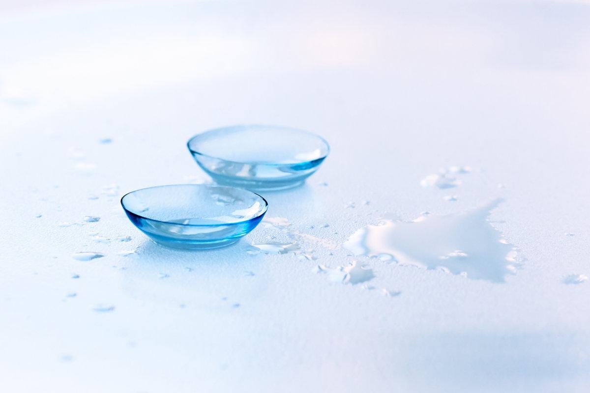 Contact lenses and water drops on light blue background. Eyewear, eyesight and vision, eye care and health, ophthalmology and optometry