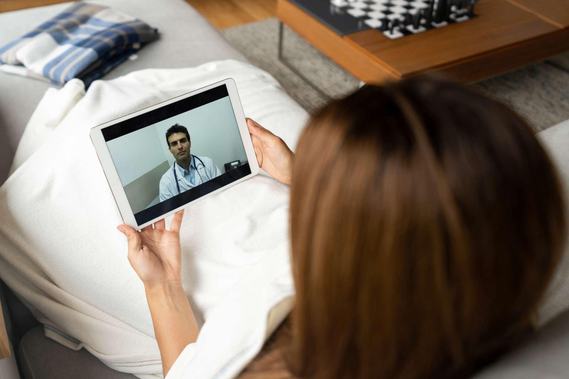 Kranke Frau in Quarantäne im Gespräch mit ihrem Arzt online über einen Tablet-Computer - Gesundheitskonzepte