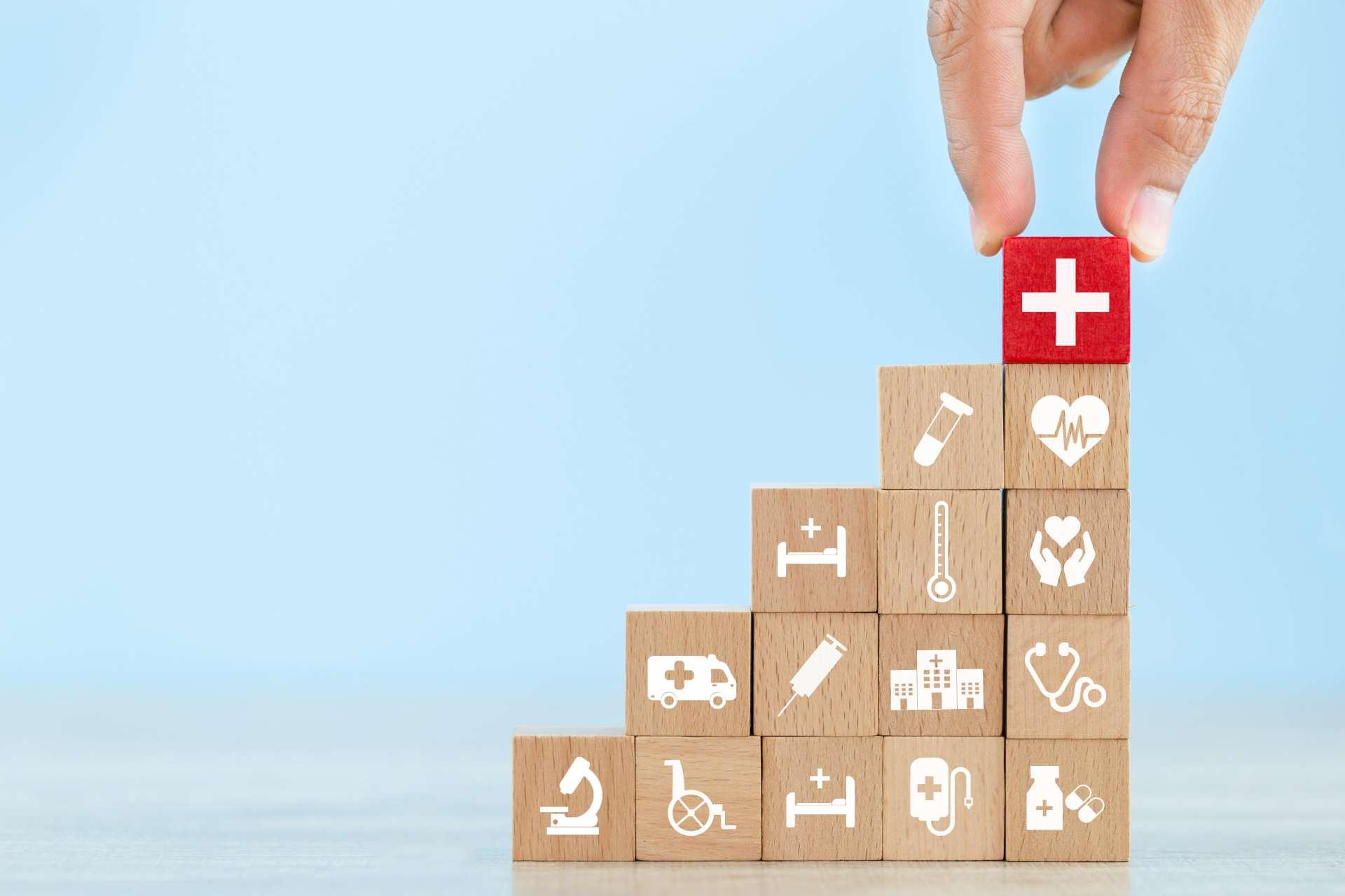 Krankenversicherungskonzept, Handanordnen von Holzblockstapeln mit Ikone Gesundheitswesen medizinisch.