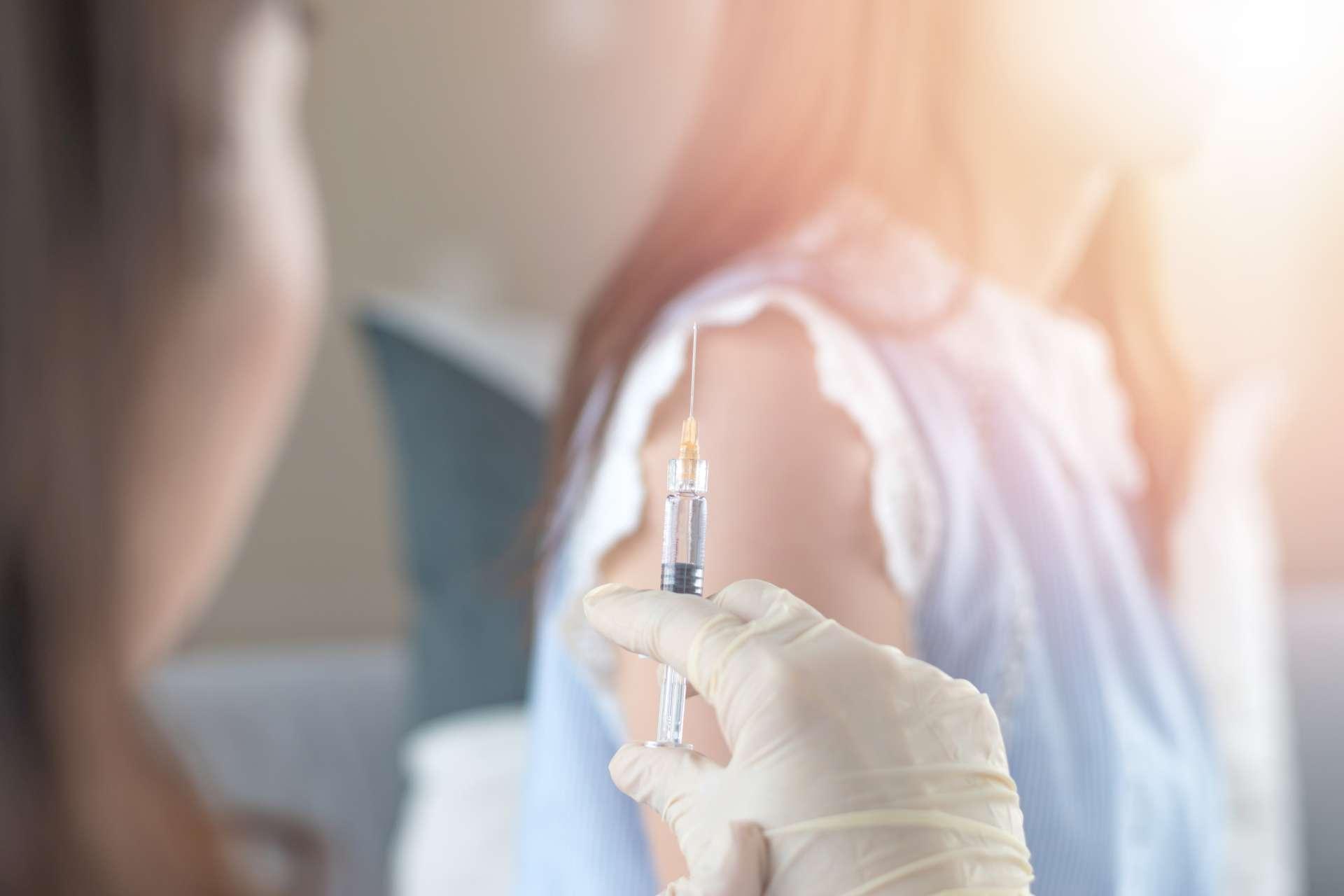 Weltimmunisierungswoche und Konzept des Internationalen HPV-Bewusstseinstages. Frau mit Impfung gegen Influenza oder Grippeimpfung oder HPV-Prävention mit Spritze durch eine Krankenschwester oder einen Arzt.