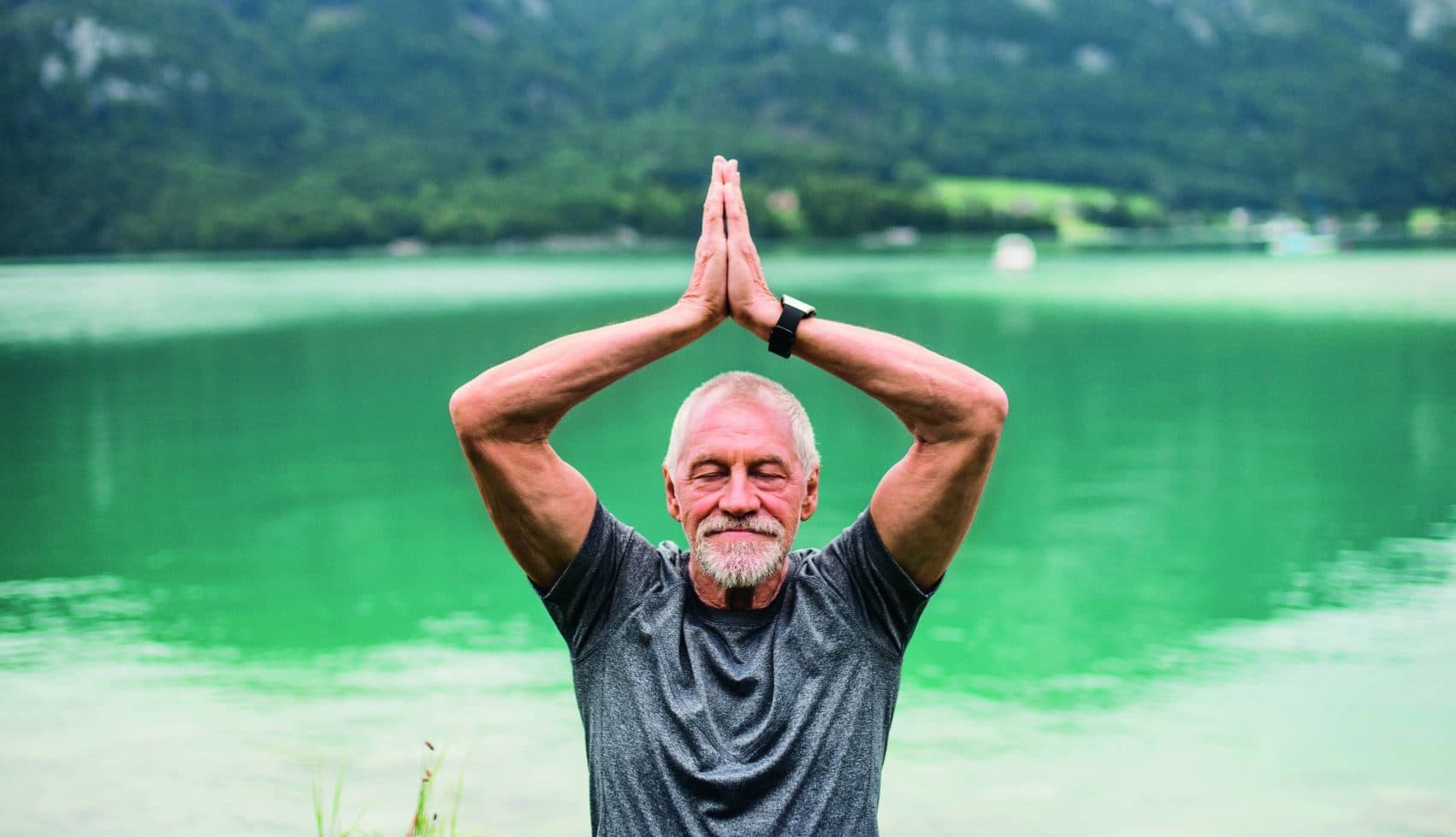Mann meditiert an einem See.