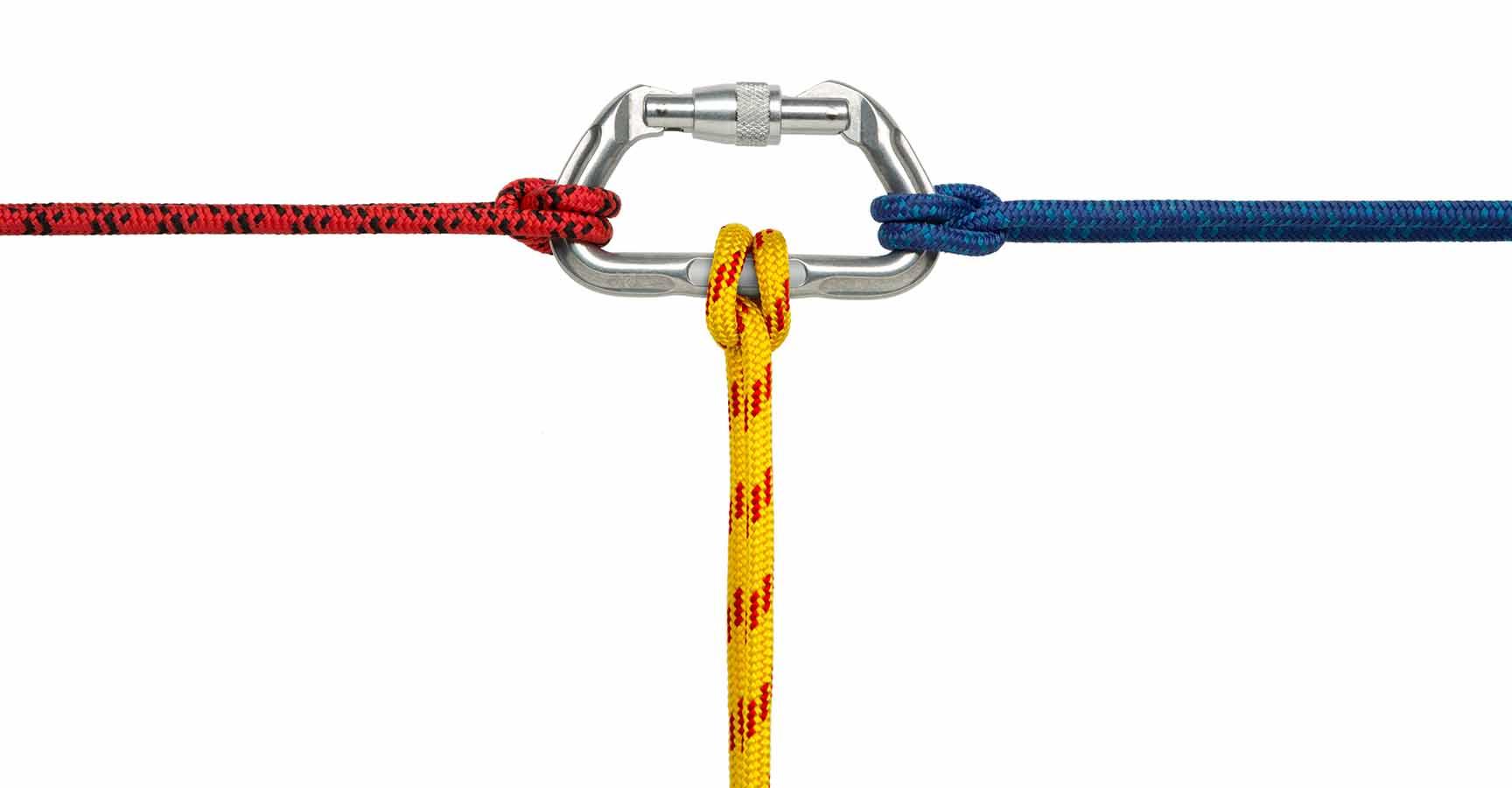 "This is a photo taken in the studio of a red, blue and yellow climbing rope attached to a carabiner with a clove hitch knot on each end isolated on a white background. There is a clipping path included.Click on the links below to view lightboxes."