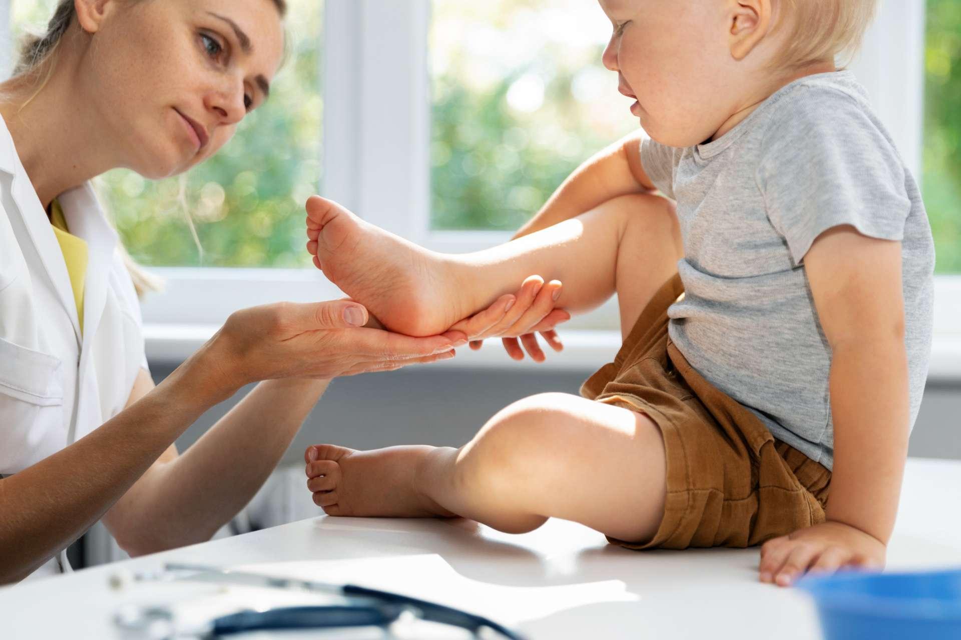 Orthopäde Podologe Überprüfung des Zustands der Füße des Kinderpatienten im Klinikbüro
