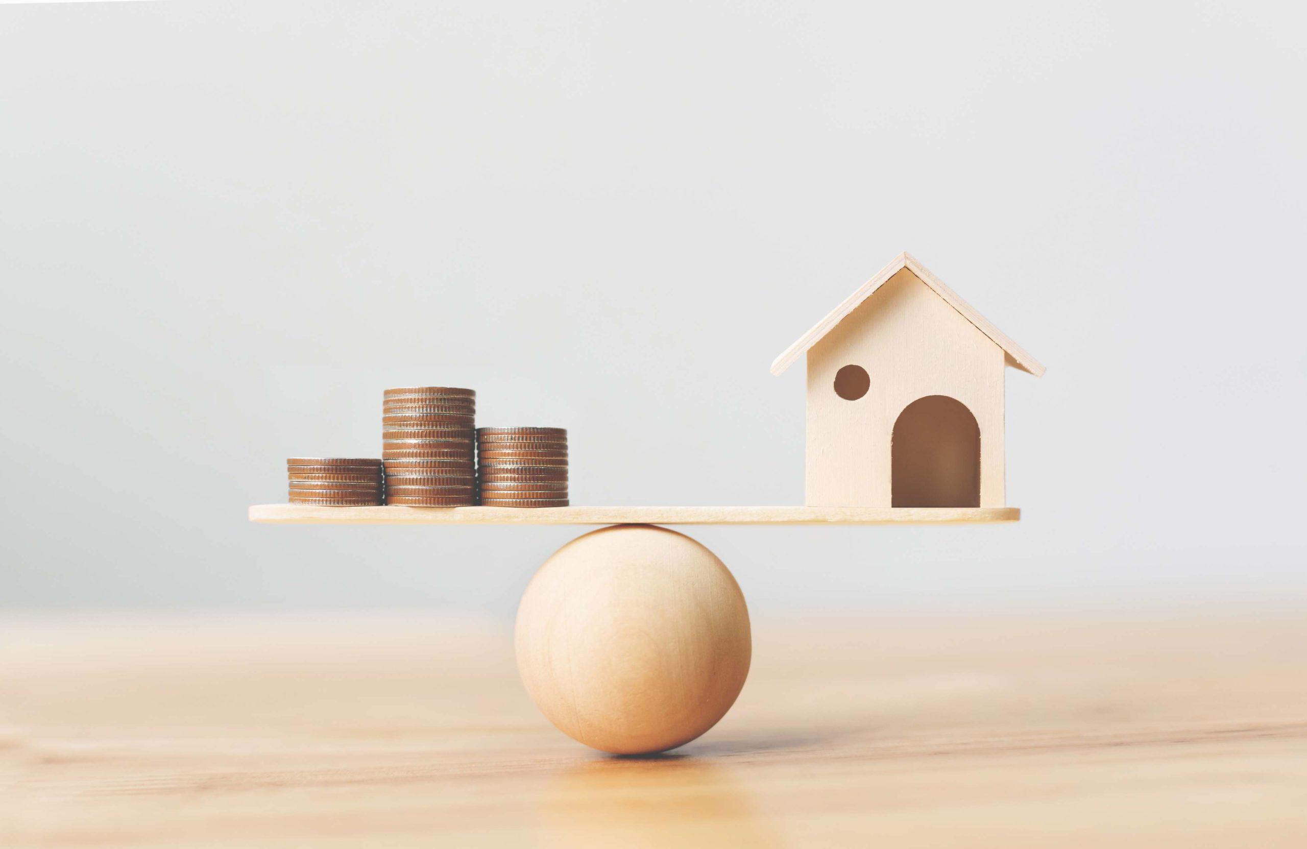 Haus- und Geldmünzen aus Holz stapeln sich auf Holzschuppen. Immobilieninvestment und Haushypothek Finanzimmobilienkonzept