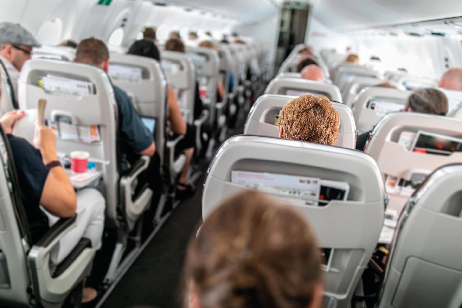 Innenraum eines Verkehrsflugzeugs mit Passagieren in ihren Sitzen während des Fluges.
