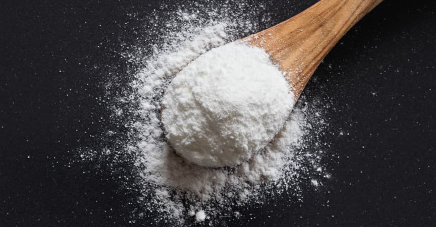 Backpulver auf einem Holzlöffel auf dunklem Hintergrund, Ansicht von oben