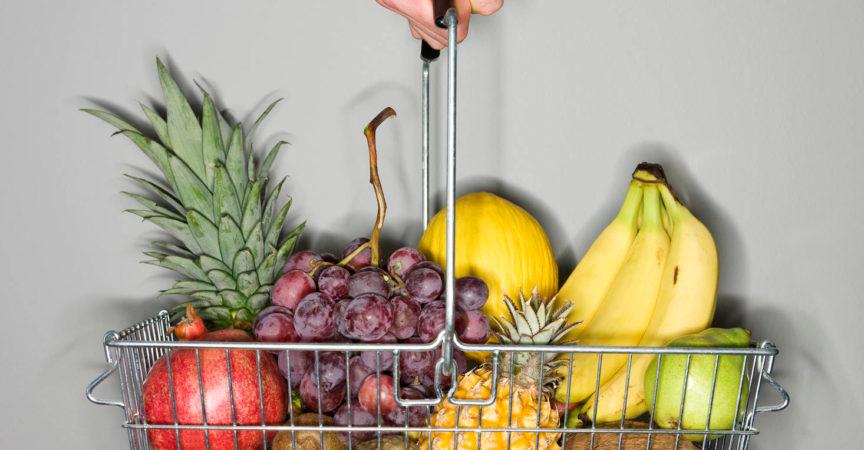 Einkaufskorb mit Früchten auf grauem Hintergrund