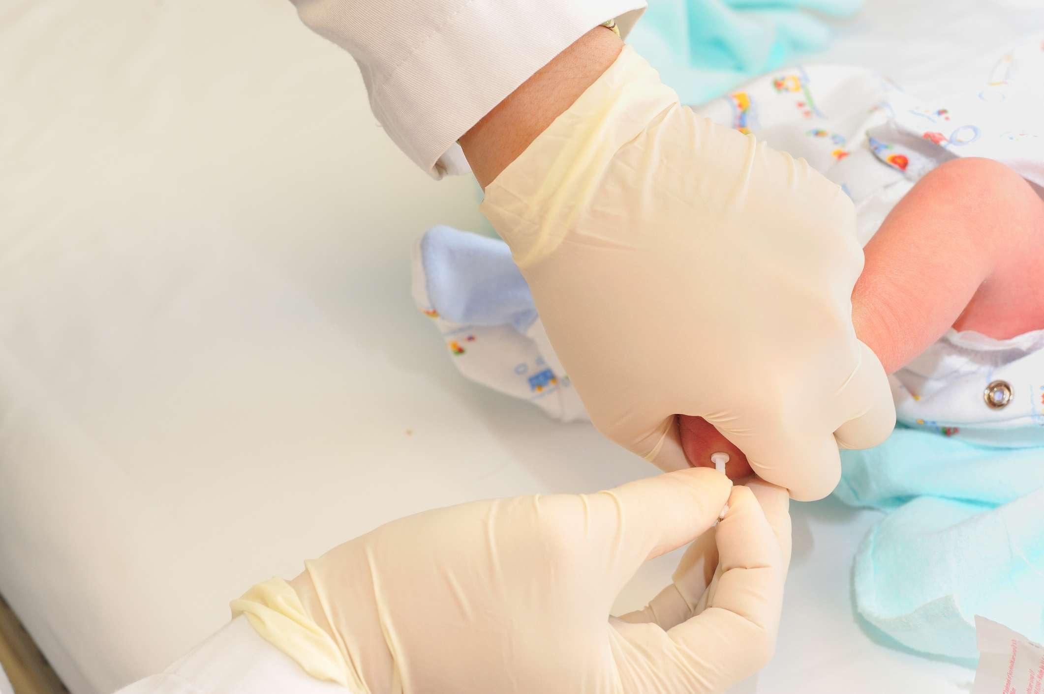 medizinische Person, die neugeborene Babyferse für Blutprobenprüfung sticht.