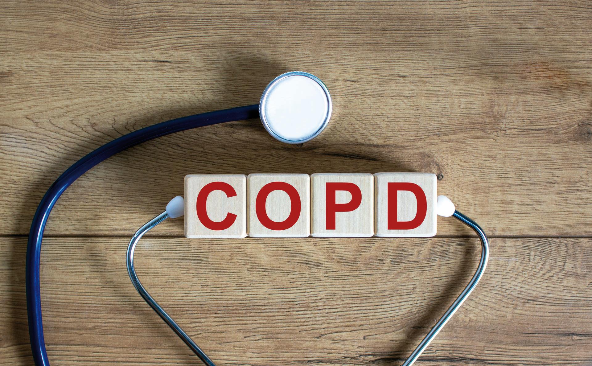 COPD medizinisches Konzept. Holzwürfel mit der Aufschrift &#8218;COPD &#8211; chronisch obstruktive Lungenerkrankung&#8216;, Stethoskop. Schöner hölzerner Hintergrund. Platz kopieren.