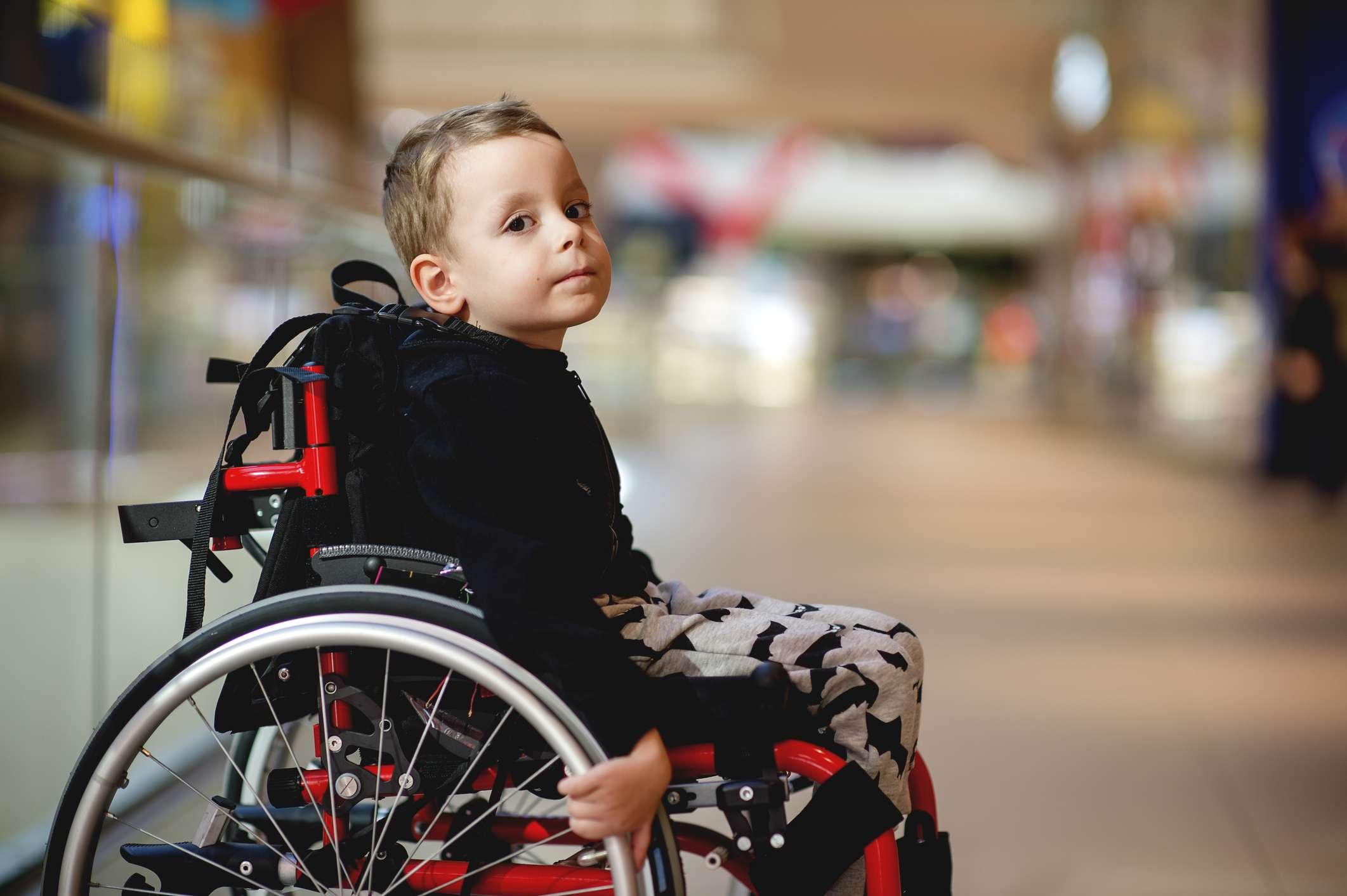 Netter kleiner Junge im Rollstuhl im Einkaufszentrum