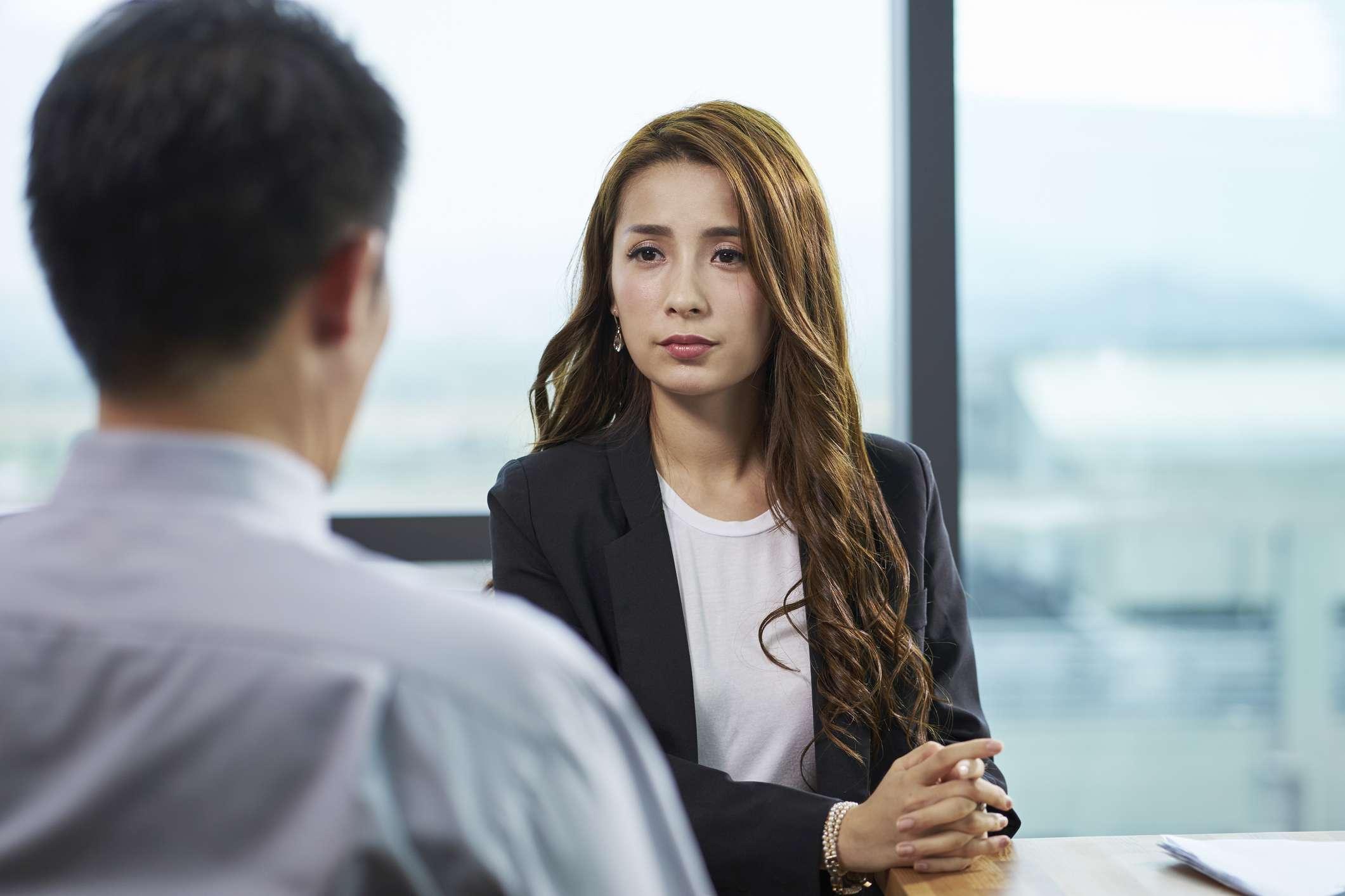 Junge asiatische Geschäftsfrau, die von HR-Manager in einem modernen Unternehmensbüro interviewt wird