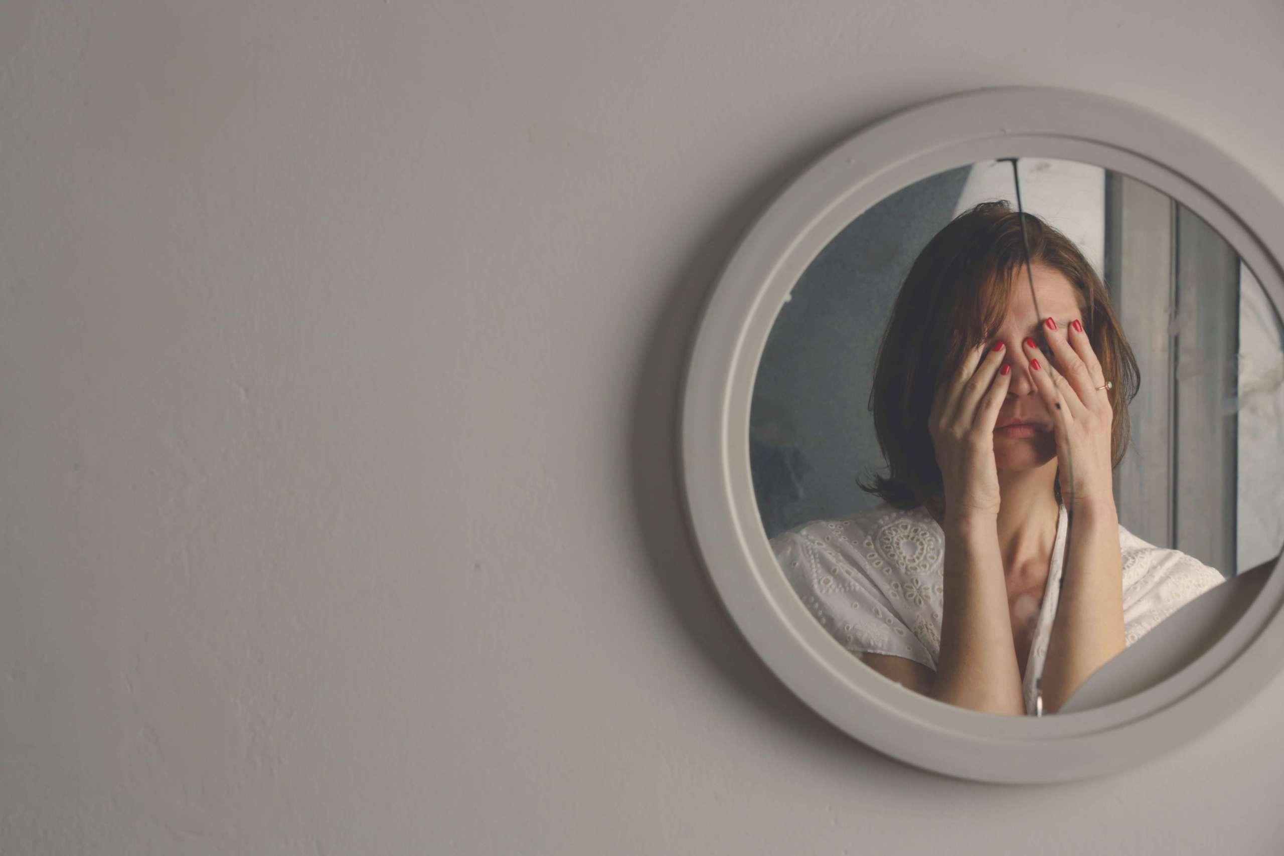 Reflexion des Gesichtes einer Frau im zerbrochenen Spiegel. Depression, Angst, Phobie, Selbstmord und psychisches Gesundheitskonzept.