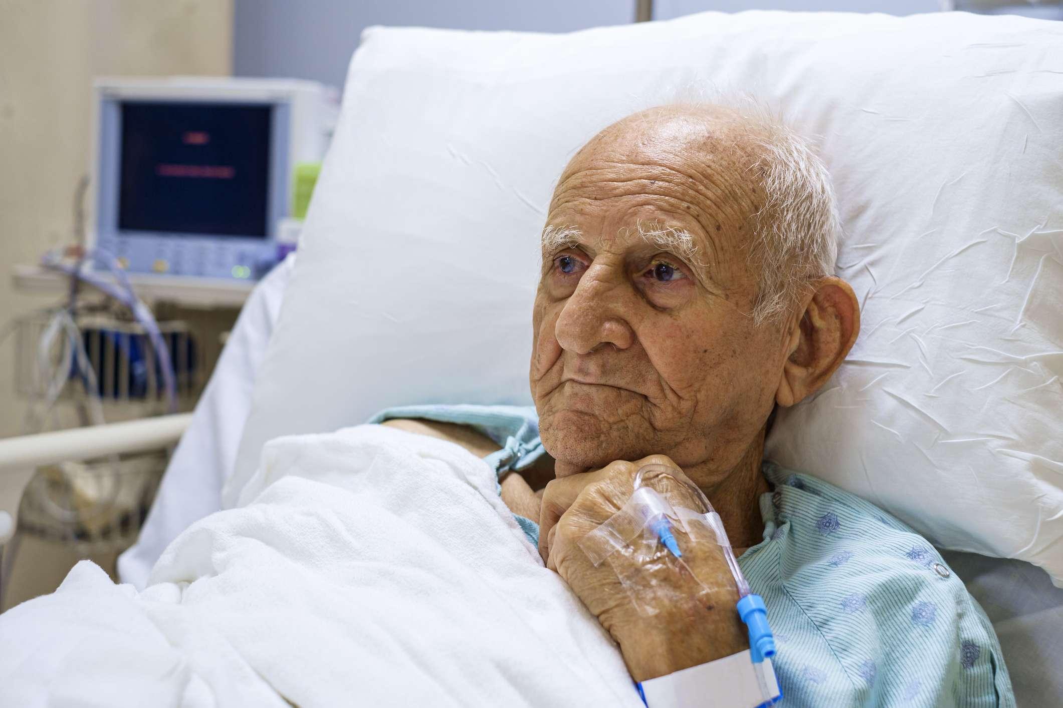 Älterer über 80-jähriger Mann, der sich von einer Operation in einem Krankenhausbett erholt.