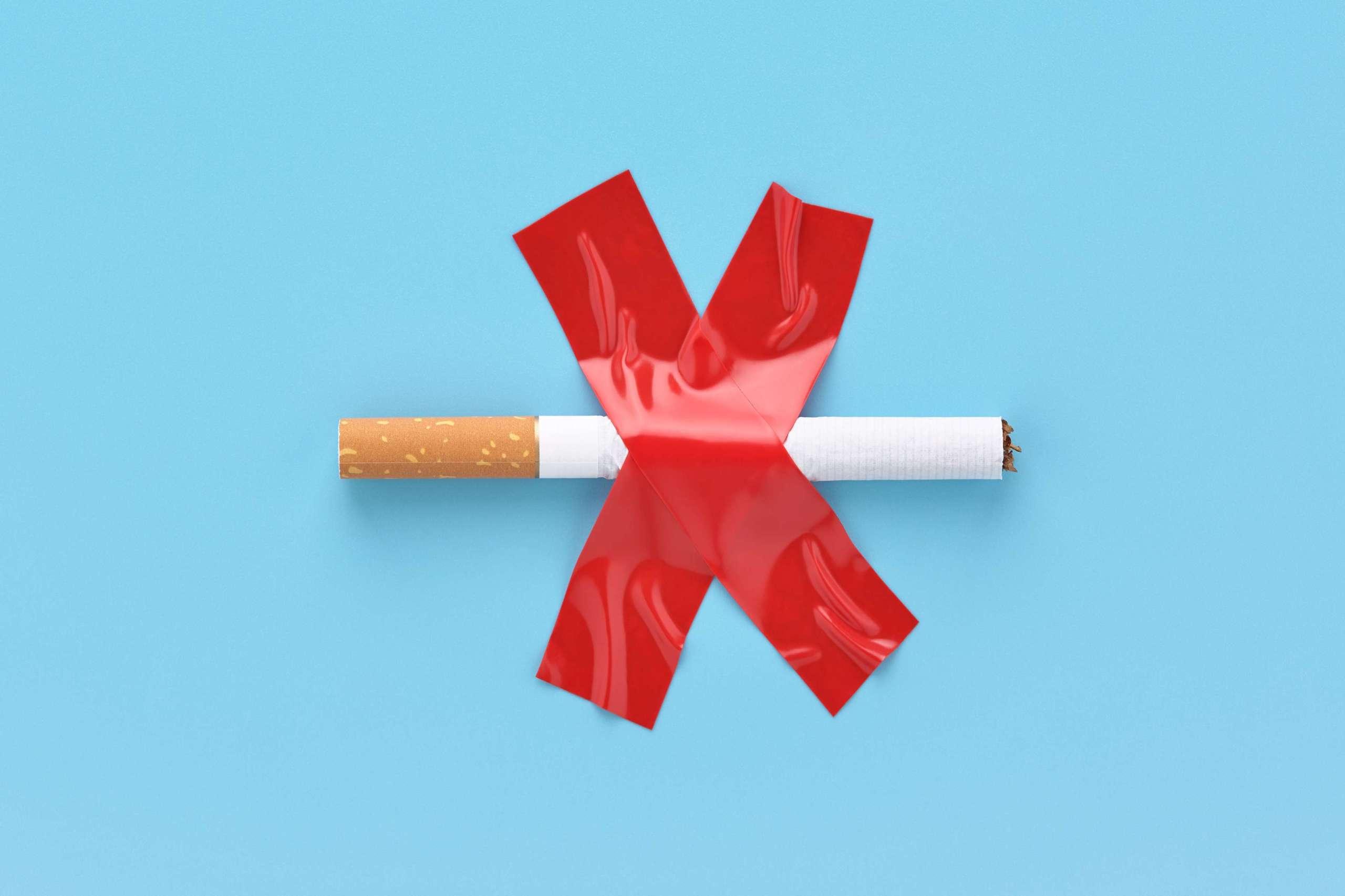 Durchgestrichene Zigarette, mit rotem Klebeband auf blauem Grund aufgeklebt. Nichtraucherkonzept.