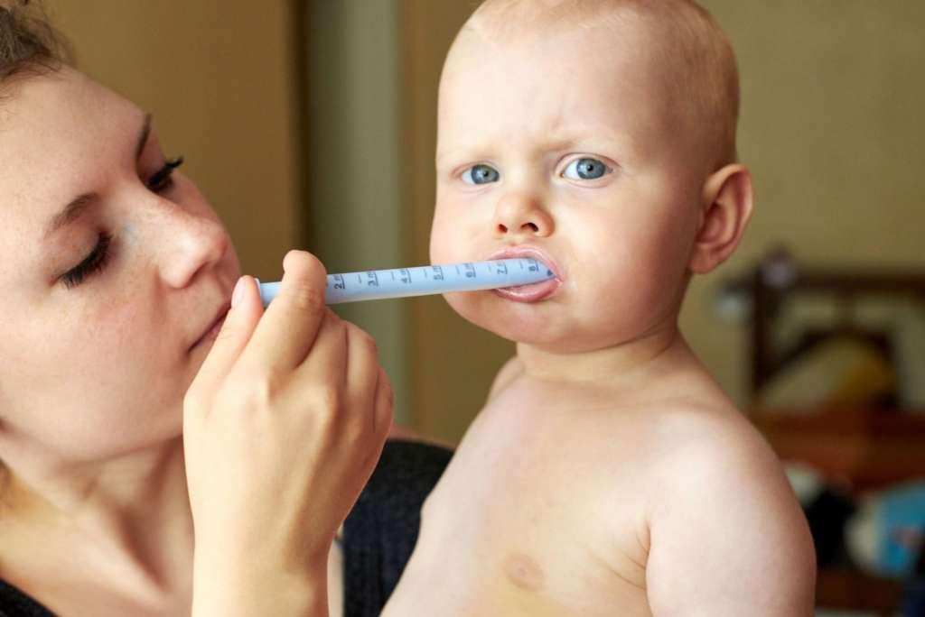 Mama gibt ihrem kleinen Kind Medizin durch eine Spritze