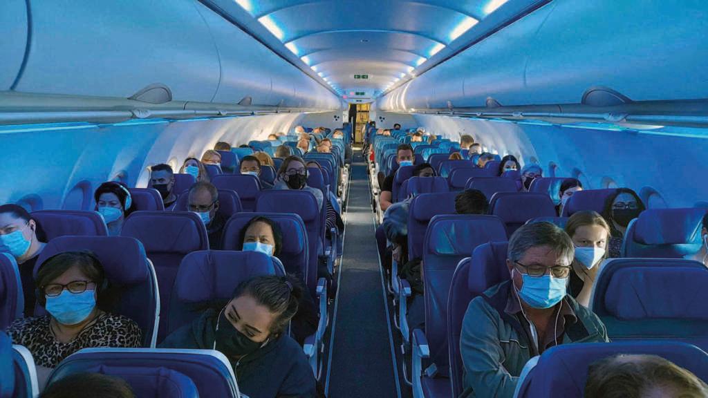 Menschen, die aufgrund von COVID-19 eine Gesichtsmaske tragen, sitzen im Flugzeug, Kanada