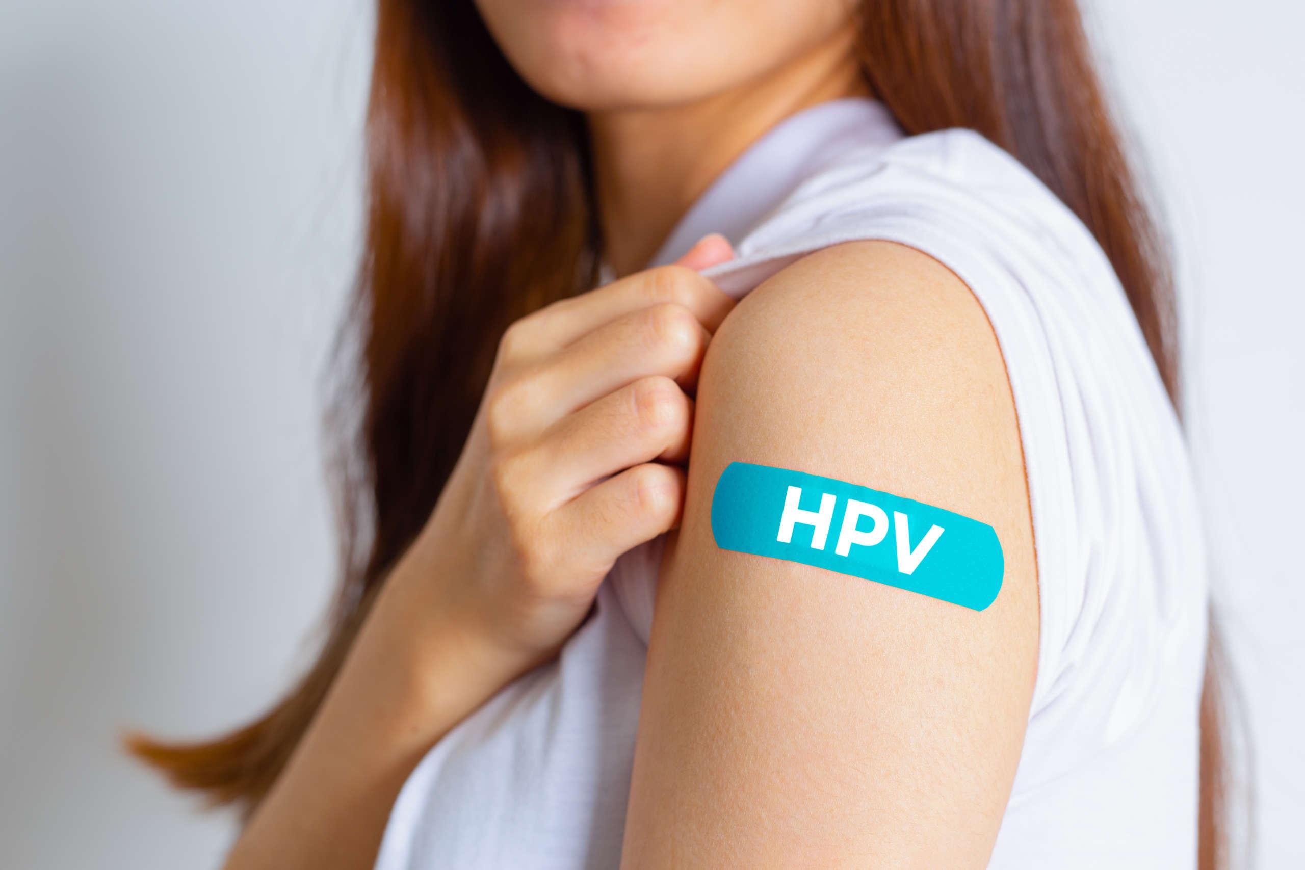 HPV (Humanes Papillomavirus) Teenager-Frau, die einen blauen Verband zeigt, nachdem sie den HPV-Impfstoff erhalten hat. Viren Einige Stämme infizieren Genitalien und können Gebärmutterhalskrebs verursachen. Frauengesundheitskonzept.