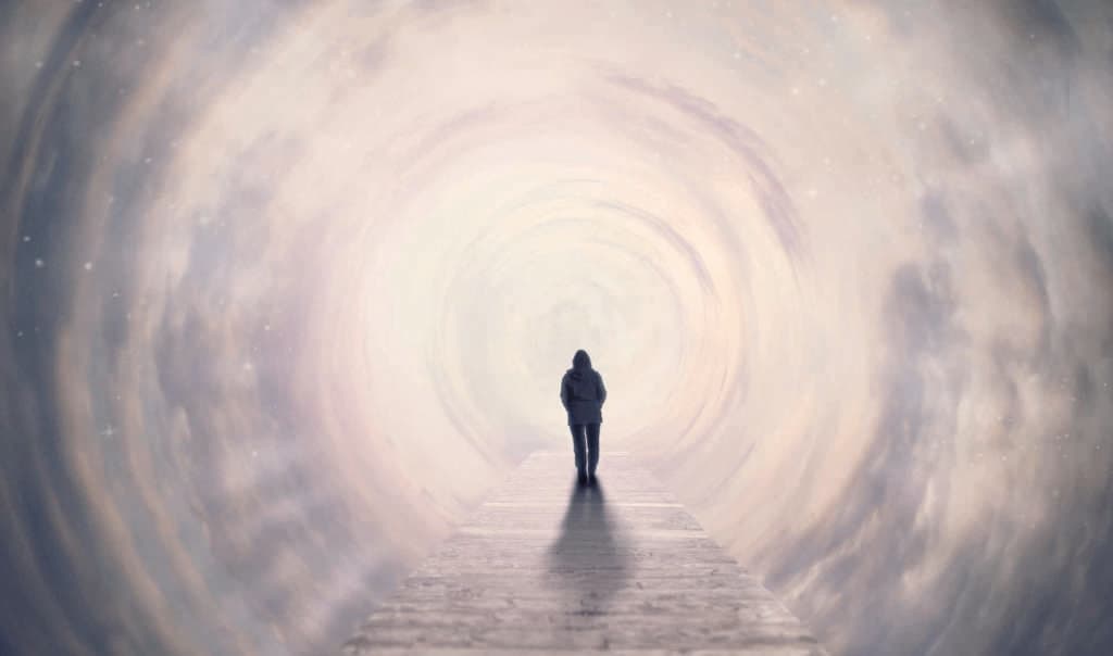Eine Frau, die auf einer Fußgängerbrücke im Wolkentunnel ins Licht geht