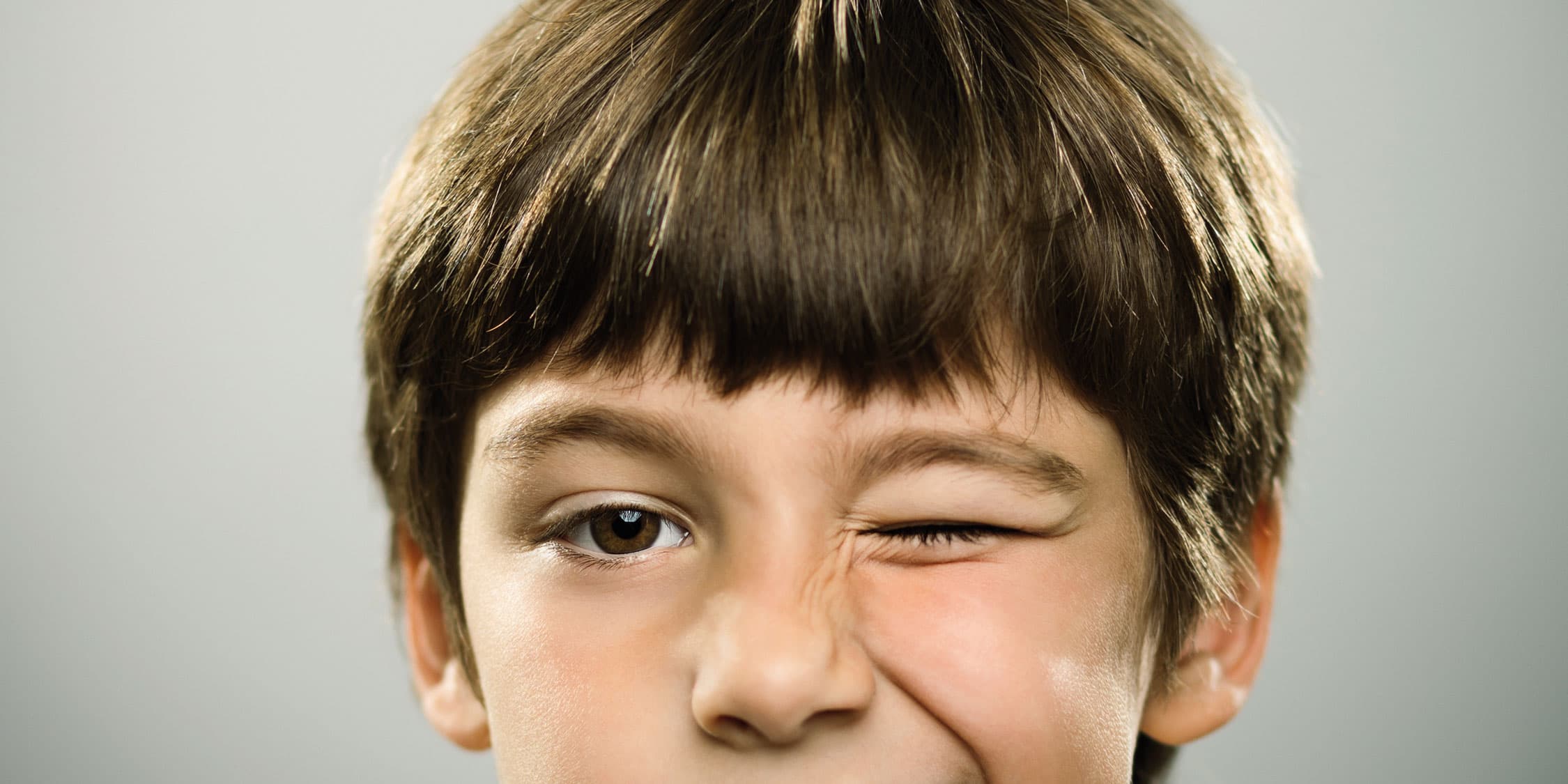 Porträt eines kaukasischen echten Jungen, der zwinkert.