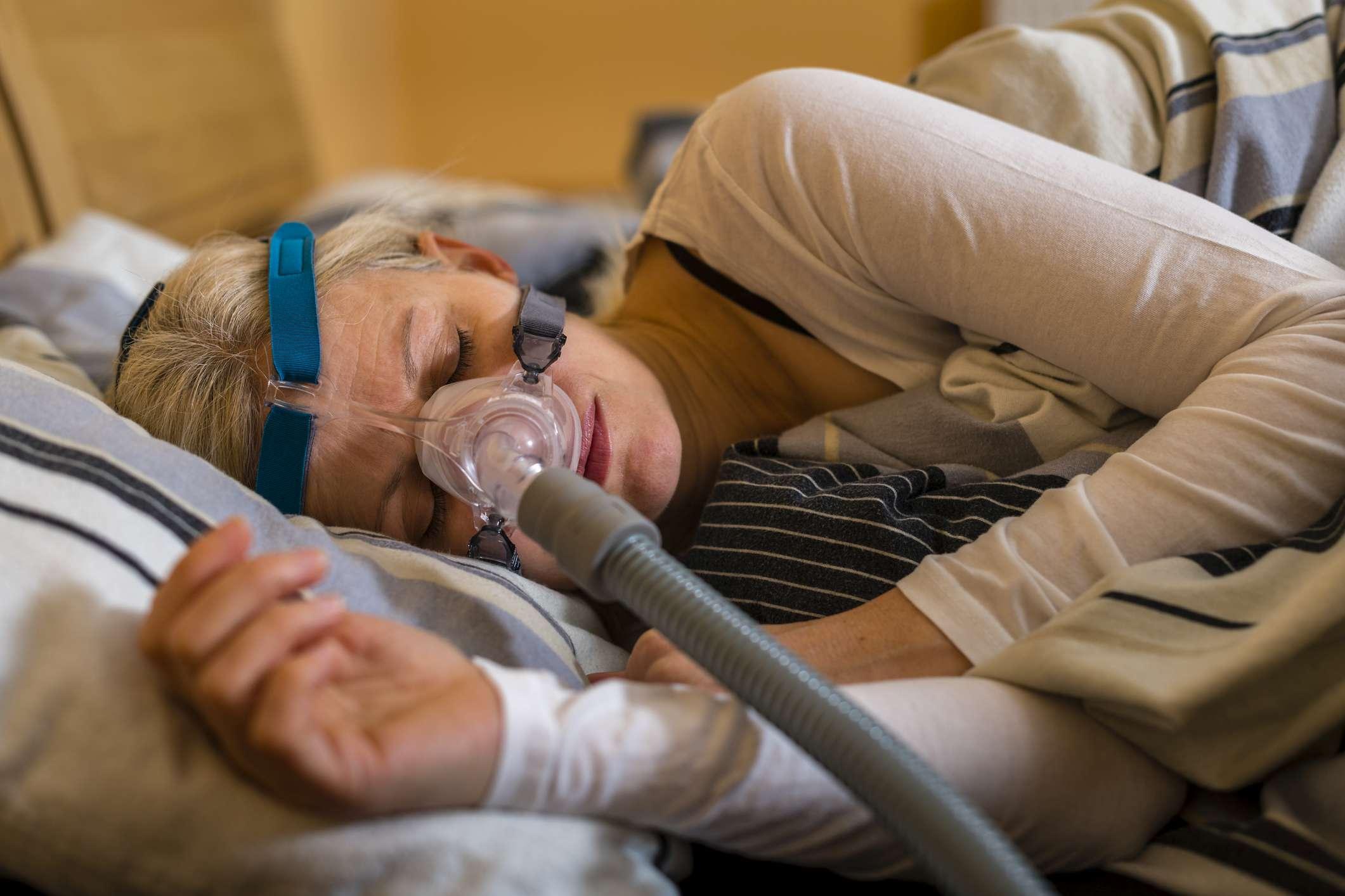 Frau, die ein cpap-Gerät verwendet, um das Ersticken und Schnarchen von obstruktiver Schlafapnoe zu stoppen