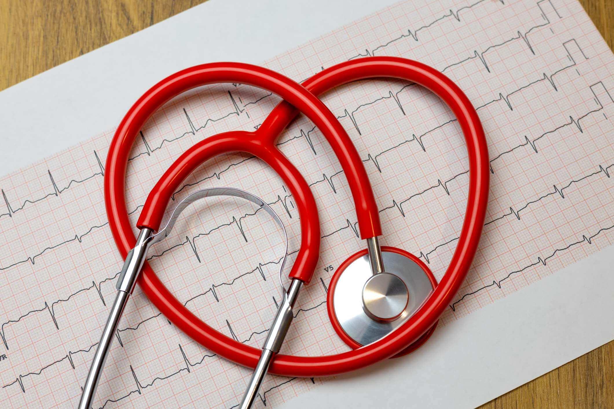 Nahaufnahme des roten Herzstethoskops auf Papier des Elektrokardiogramms (EKG).