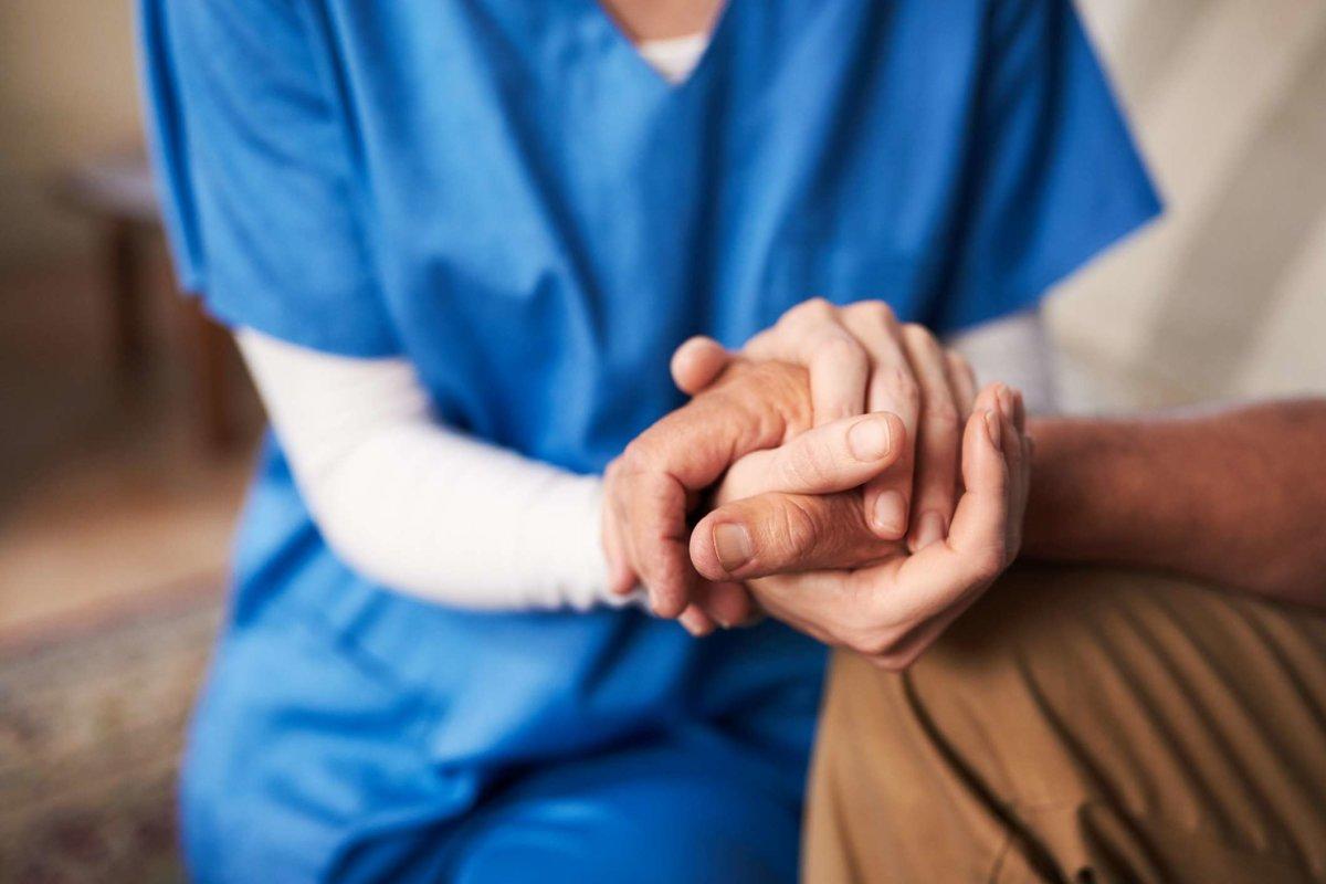Schnappschuss einer Krankenschwester, die die Hand ihres älteren Patienten hält