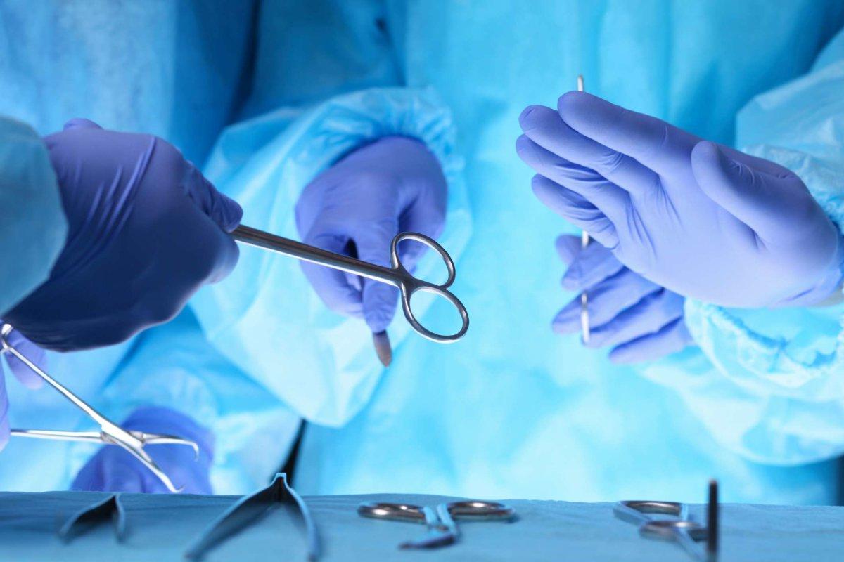Chirurgen halten eine chirurgische Schere in der Hand und reichen chirurgisches Gerät vorbei, Nahaufnahme. Gesundheits- und Veterinärkonzept.