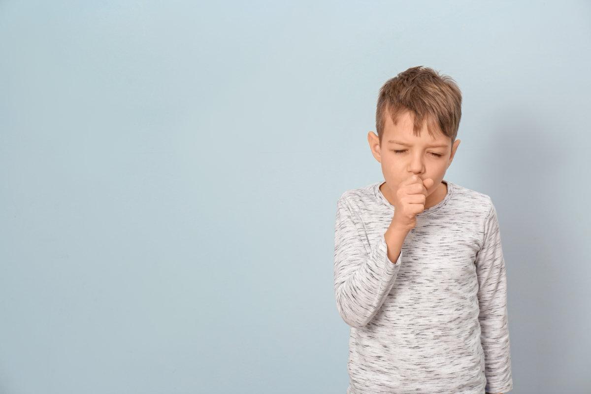 Little boy coughing on light background