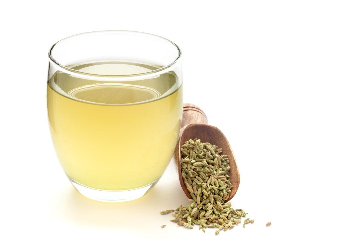 Close-Up of original  organic boiled water (Tea or kada ) with Sonf  or Fennel seed ( Foeniculum vulgare ) in a transparent glass cup over white background. Original residue in bottom of tea cup