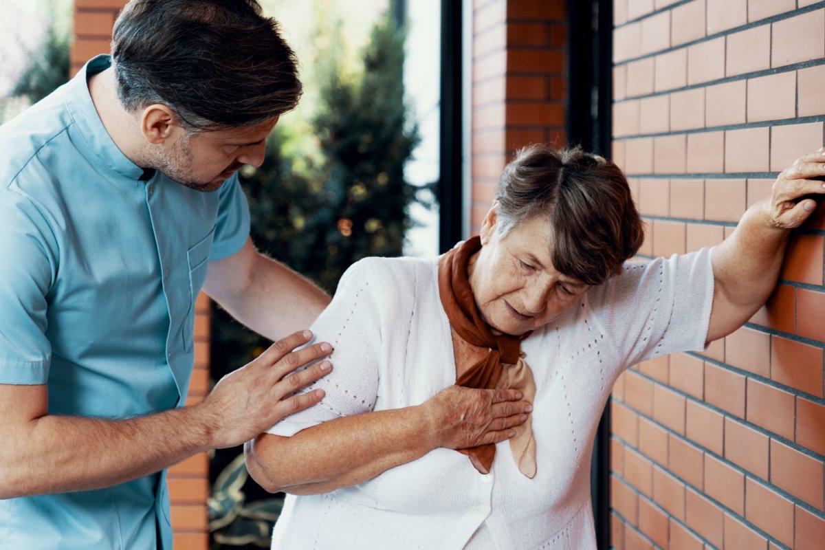 Krankenpfleger hilft kranker älterer Frau mit Brustschmerzen