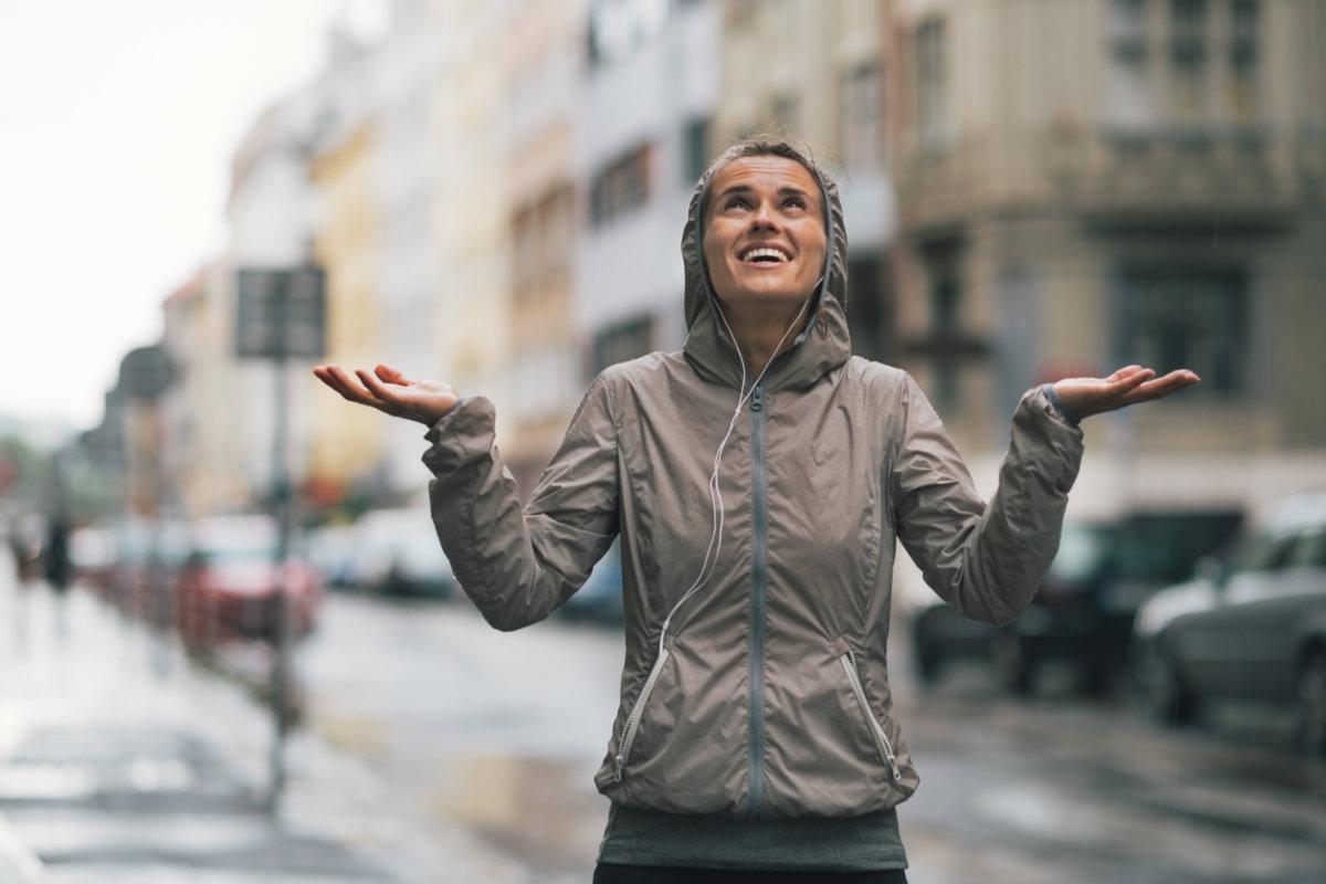 Fröhliche Fitness junge Frau fängt Regentropfen in der Stadt