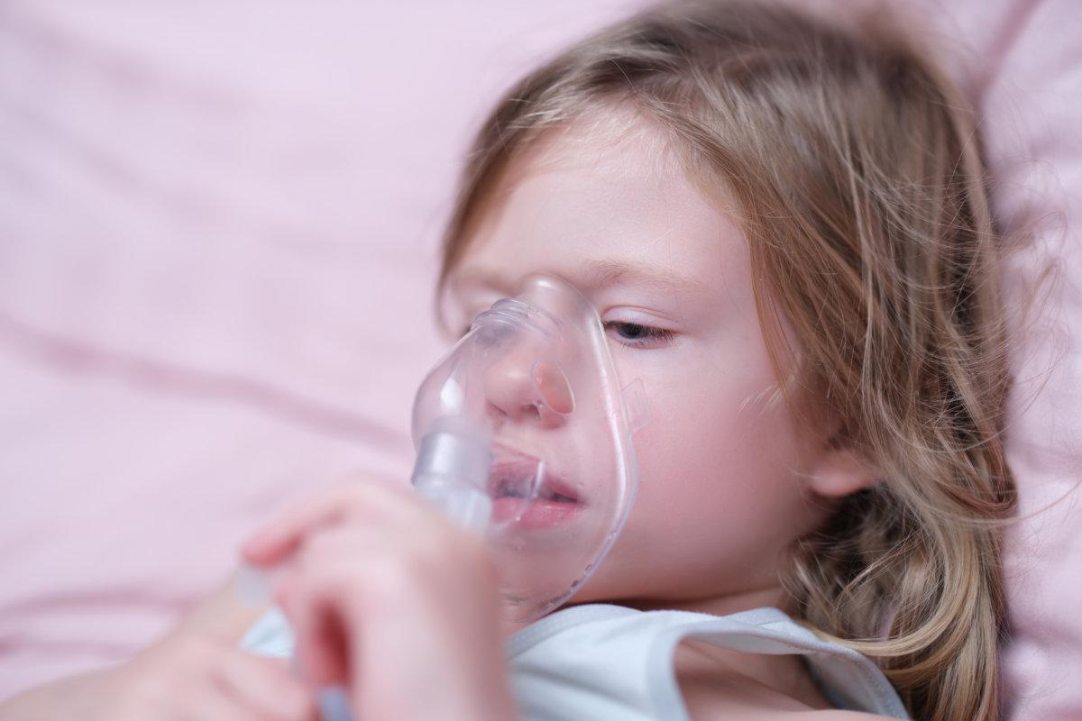Kleines Mädchen inhaliert mit einem Vernebler ein hormonelles Medikament