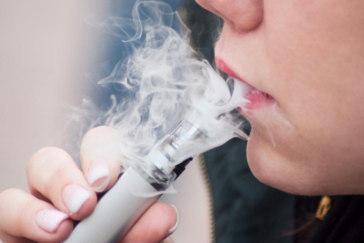 Nahaufnahme des Mundes einer Frau mit E-Zigarette im Freien