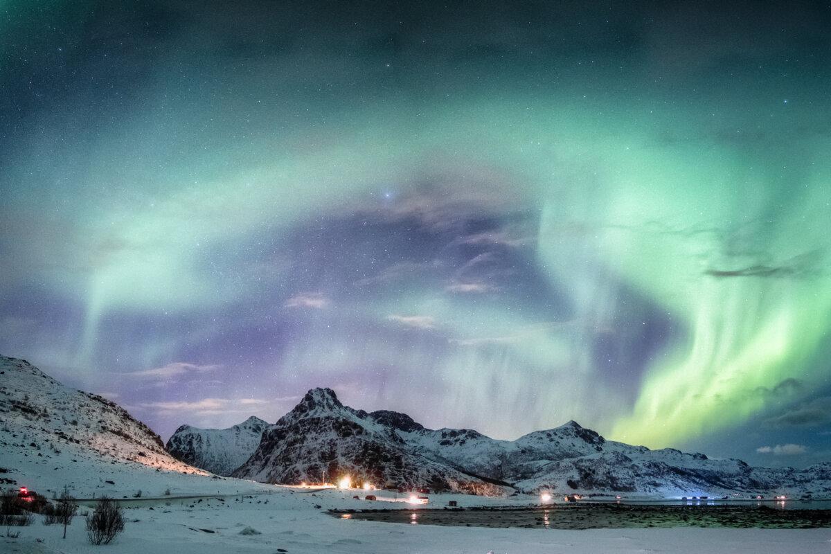 Nordlichtexplosion auf einer verschneiten Bergkette nahe der Küste der Lofoten-Inseln, Norwegen