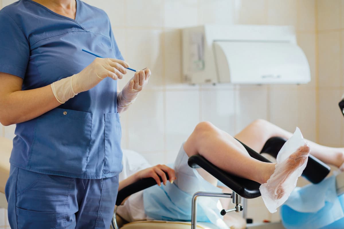 Unbekannte Gynäkologin arbeitet mit Patientin. Vaginalabstrich.